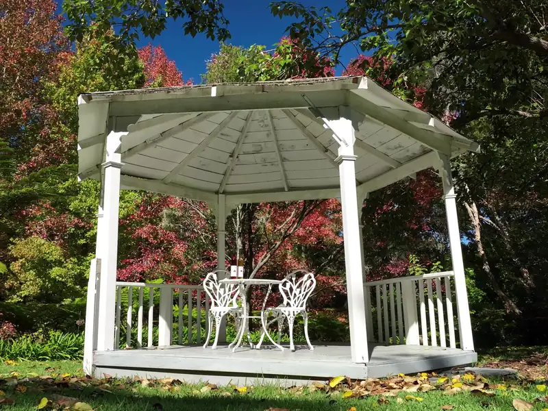 A white garden gazebo framed by red autumn maples at Fires Creek